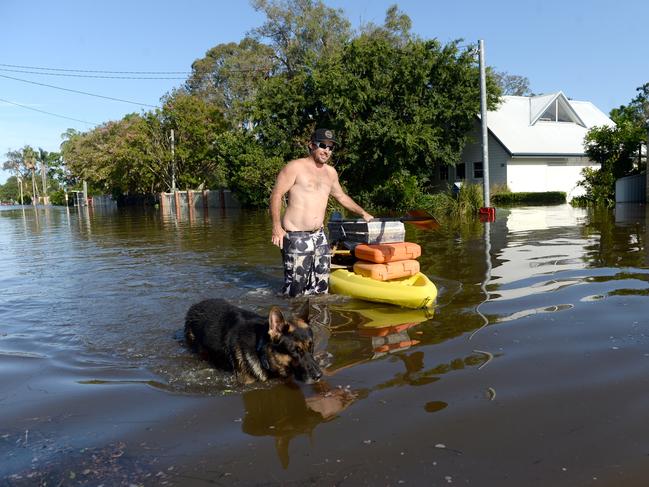 Scott Bennett floats his tools through the flooded street of Geoffrey Road in Chittaway Bay. Picture: Jeremy Piper