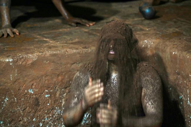 A wrestler showers himself with mud from the wrestling pit
