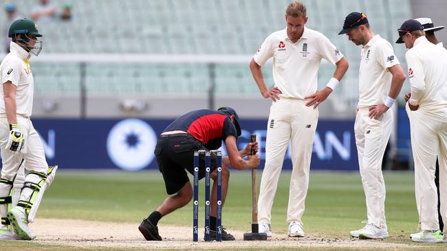 A MCG groundskeeper hammers the pitch with a sledgehammer.