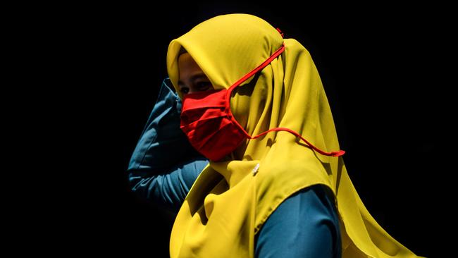 A woman wearing a face mask, as a precautionary measure against the spread of the COVID-19 coronavirus, walks through a market in Banda Aceh on March 24, 2020. Picture: Chaideer Mahyuddin/AFP