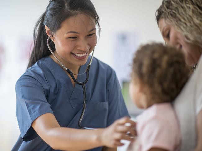 A nurse is listening to a little girl's heartbeat at a doctors appointment.