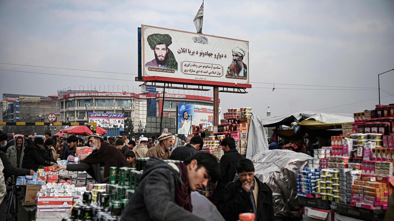 People shop as a billboard displaying the Taliban founder and late supreme leader Mullah Omar and late leader of the Haqqani militant network Jalaluddin Haqqani is seen at a market in Kabul. Picture: AFP
