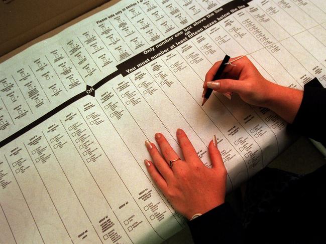 MARCH 26, 1999 : Voter struggles to mark tablecloth-sized NSW Upper House ballot paper with pencil tied to short string while casting an early vote in 27/03/99 State election, 26/03/99. Pic Marc McCormack.