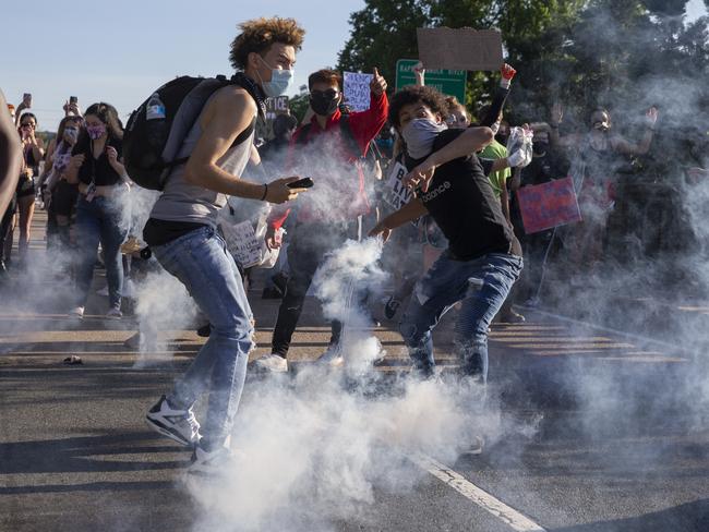 Protesters throw a tear gas canister back toward Stafford County deputies on the Falmouth Bridge in Fredericksburg, Virginia. Picture: AP