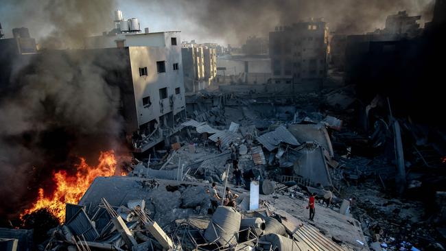 Smoke and fire rise from a levelled building as people gather amid the destruction in the aftermath of an Israeli strike on Gaza City on October 26. Picture: AFP