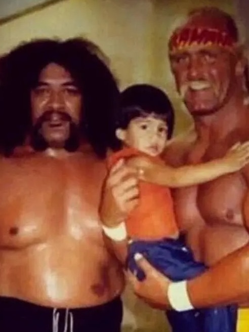 Sika Anoa’i (L) stands with Hulk Hogan (R), who is holding Anoa’i’s son Joe, aka Roman Reigns.