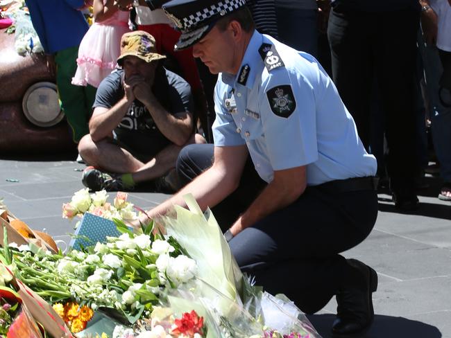 A police officer lays flowers at a public memorial site for the BourkeSt tragedy on Sunday. Picture: David Crosling