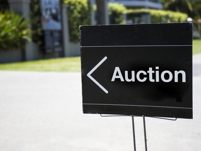 Auction sign, outside suburban home, positioned on front lawn.