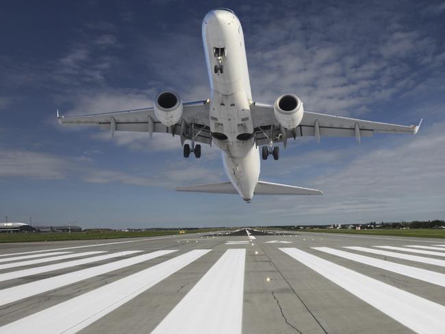 Plane taking off at the end of the runway with outstretched landing gear