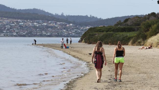 People walking along Nutgrove Beach, Sandy Bay. Picture: LUKE BOWDEN