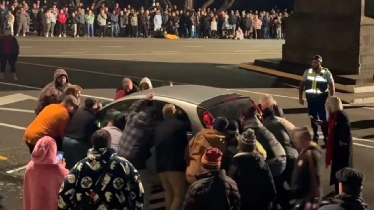 A group of men banding together to move the car. Picture: Facebook/RNZ