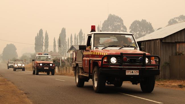 Tasmania Fire Service personnel lead out cars evacuating from Fourfoot Rd, Geeveston. Picture: LUKE BOWDEN