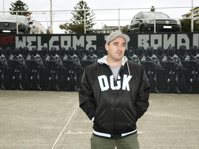 Artist Luke Cornish, pictured with his mural, has said the artwork was not an attack on border force officers of the government, but aimed at people on the beach “sticking their fingers in their ears” ignoring deaths in off-shore detention. Picture: John Appleyard