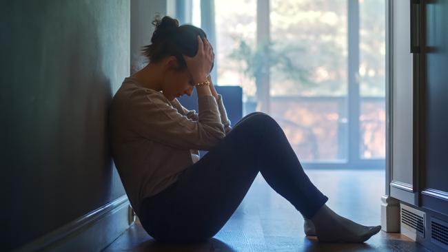 istock generic:  woman, abuse, DV, domestic violence, harassment, sexual harassment.   Sad Young Woman Sitting on the Floor In the Hallway of Her Appartment, Covering Face with Hands. Atmosphere of Depression, Trouble in Relationship, Death in the Family. Dramatic Bad News Moment . Picture: istock