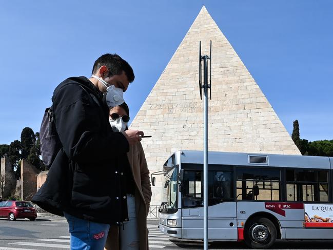 A couple next to the deserted Pyramid of Cestius crossroads in Rome. Picture: AFP