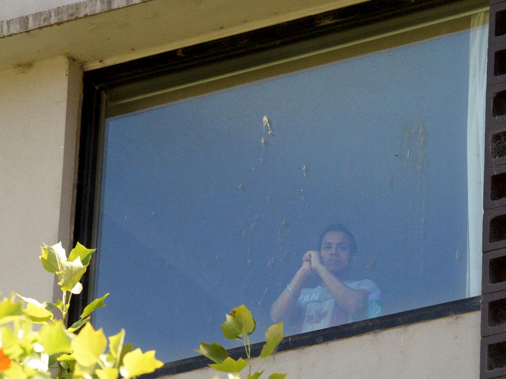 A refugee looks out a window at the Park Hotel in Carlton, Victoria, as other asylum seekers were released after more than eight years in detention. Picture: Andrew Henshaw
