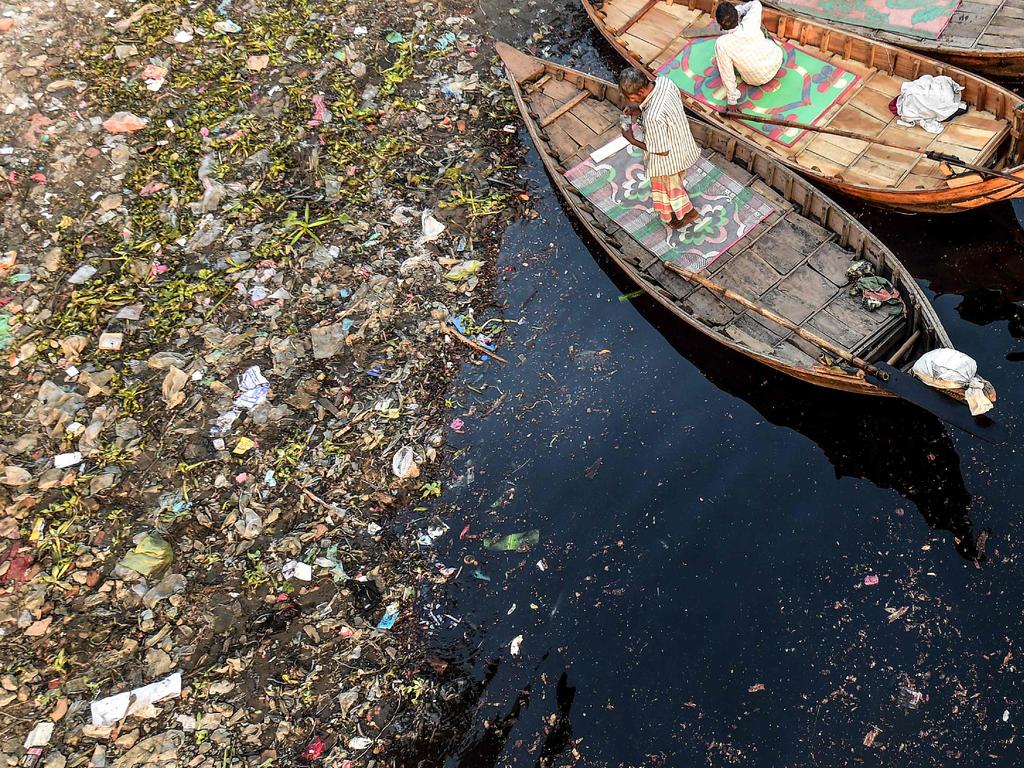 Men wait for passengers as plastic bags float on the water surface of the Buriganga river in Dhaka on January 21, 2020. - Bangladesh's high court has ordered the shutdown of 231 factories that have contributed to Dhaka's main river becoming one of the world's most polluted, a lawyer said on January 21. (Photo by MUNIR UZ ZAMAN / AFP)