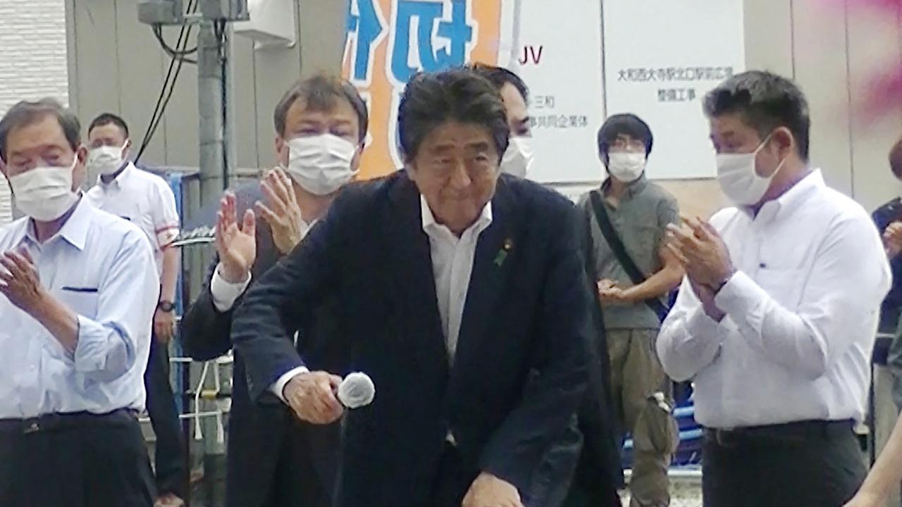 Shinzo Abe pictured with the suspected shooter watching behind him shortly before the former prime minister was shot. Picture: AFP