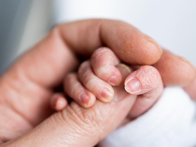 Hand of newborn baby who has just been born holding the finger of his father's hand.CREDIT ISTOCK