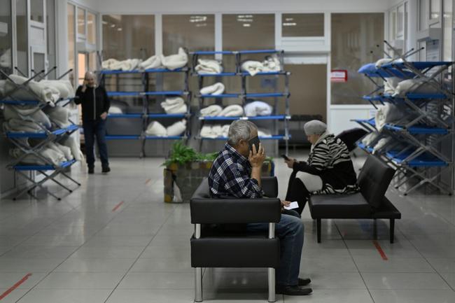 People who came through the humanitarian corridor from Russia's Belgorod region check their phones at a humanitarian centre in Sumy