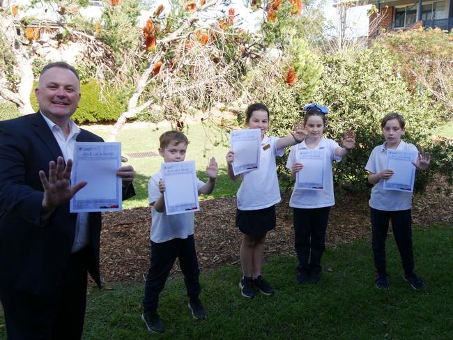 Students from Chertsey Primary School trace handprints for the totems, assisted by Central Coast Parliamentary Secretary Adam Crouch.