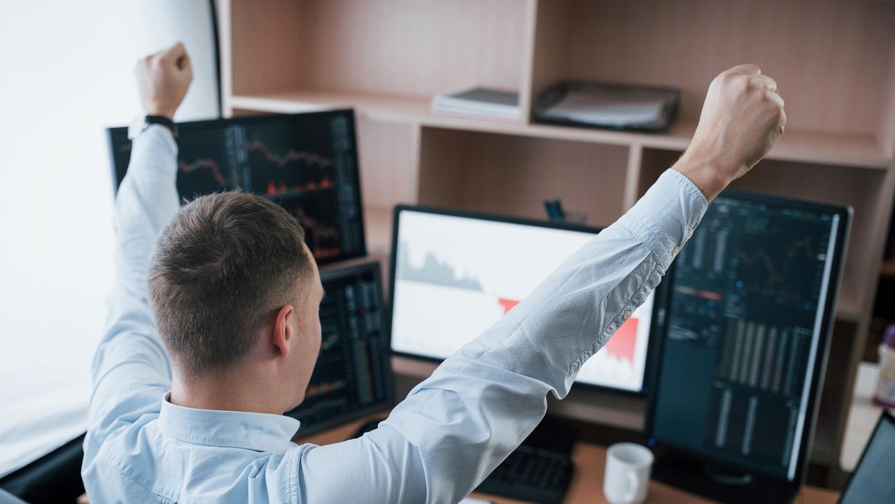 Hands up because of success. Man working online in the office with multiple computer screens in index charts. happy investor generic