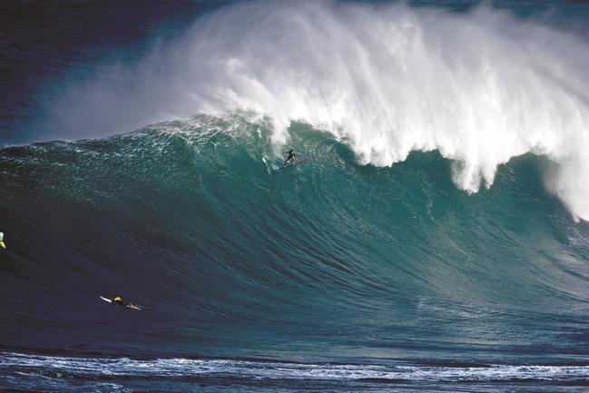 A surfer in <span id="U3211445233956L" style="font-weight:normal;font-style:italic;">The Big Wave Project</span>, at the top of a monster wave.