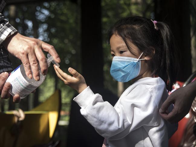 An employee gives out hand sanitiser to a girl in Zhongshan Park in Wuhan.