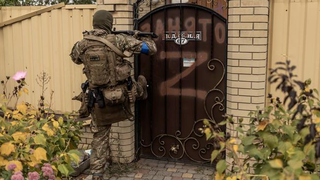 A Ukrainian soldier kicks the gate of a house that was occupied by Russian forces in Lyman. Photographs by Manu Brabo for The Wall Street Journal