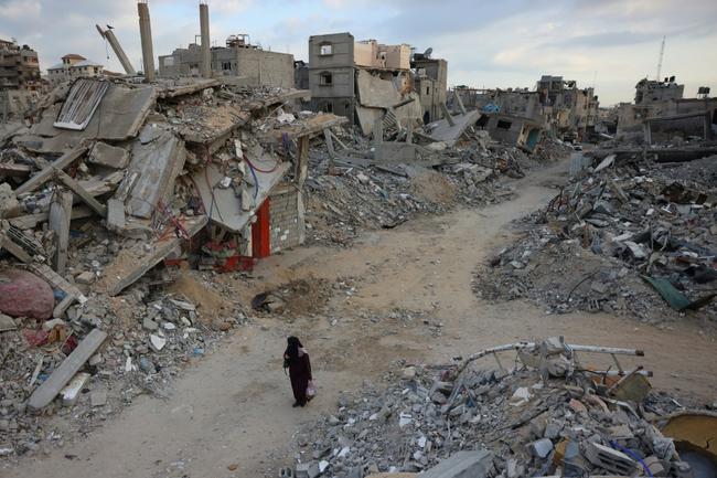 A woman walks past destroyed buildings in Khan Yunis in the southern Gaza Strip