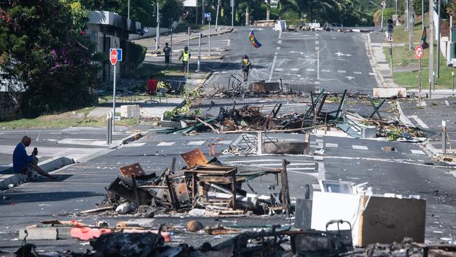 A street blocked by debris and burnt-out items following overnight unrest in the Magenta district of Noumea. Picture: Delphine Mayeur/AFP