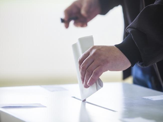 Hand of a person casting a ballot at a polling station during voting. election voting vote polling poll generic Townsville