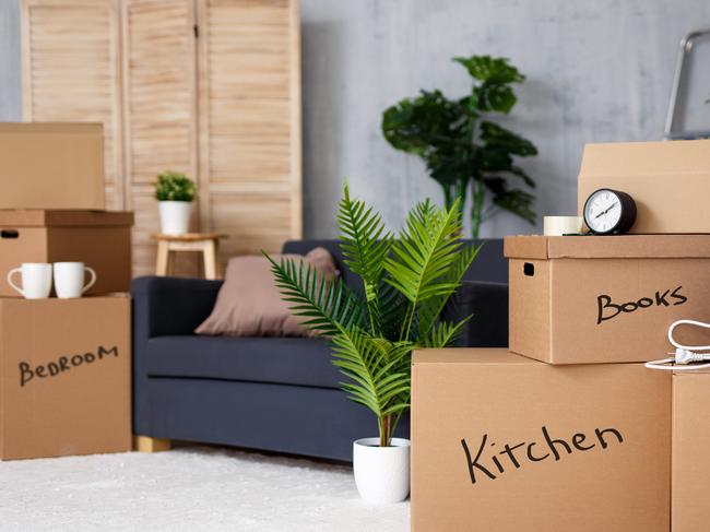 moving to new house - brown cardboard boxes with belongings stacked in living room after moving day