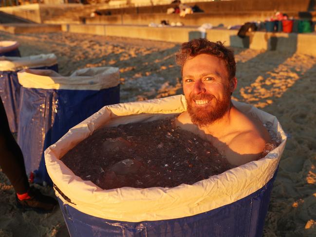 A man sits on Coogee Beach at 6am in a bucket of ice as part of a breathing program to help with cardiovascular health. Picture: John Grainger