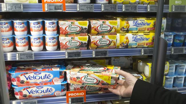 A man takes a yogurt pack from a refrigerator in a supermarket in Paris, Thursday, March 12, 2015. France's competition authority handed the country's top yogurt makers euro192 million ($203 million) in fines Thursday for fixing prices over the course of several years, striking secret deals in hotel rooms and on special phone lines created to avoid detection. (AP Photo/Michel Euler)