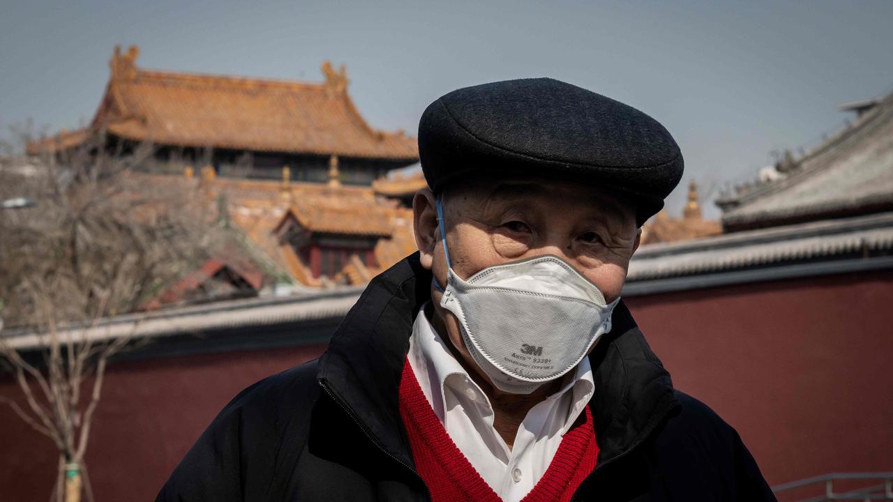 A man wearing a protective face mask to protect against the coronavirus walks on a street outside the Lama Temple.