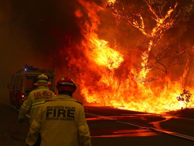 SYDNEY, AUSTRALIA - DECEMBER 19: Fire and Rescue personal run to move their truck as a bushfire burns next to a major road and homes on the outskirts of the town of Bilpin on December 19, 2019 in Sydney, Australia. NSW Premier Gladys Berejiklian has declared a state of emergency for the next seven days with ongoing dangerous fire conditions and almost 100 bushfires burning across the state. It's the second state of emergency declared in NSW since the start of the bushfire season.  (Photo by David Gray/Getty Images) *** BESTPIX ***