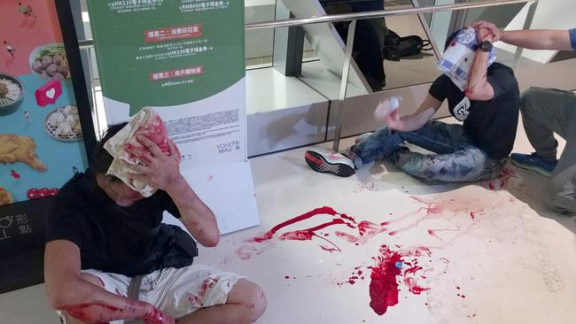 Two men in black shirts cover their heads as they bleed after being attacked by thugs in white shirts at a subway station in Hong Kong. Picture: Apple Daily via AP