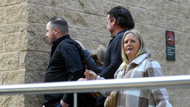 Nikita Johnson is shielded by supporters as she leaves court.