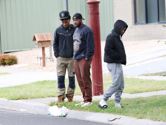 Three men place flowers at the scene on Thursday. Picture: David Crosling