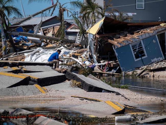 A man sits on a broken section of the Pine Island Road two days after Hurricane Ian tore into the coastline as one of the most powerful storms ever to hit the United States. Picture: AFP