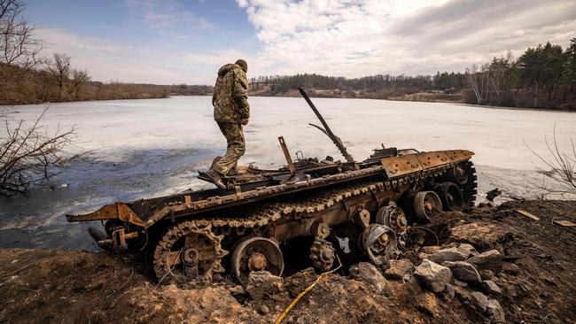 A Ukrainian serviceman stands near a destroyed Russian tank in the northeastern city of Trostianets. Picture: AFP