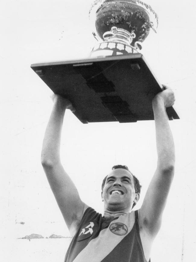  Peter Carey holds aloft the Thomas Seymour Hill trophy aloft after Glenelg beat North Adelaide in the 1986 grand final. 