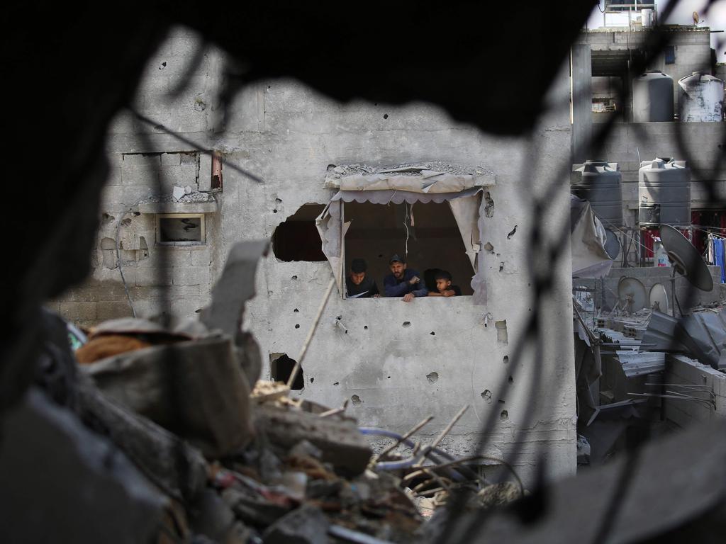 Palestinians look at the destruction from the window of a damaged house in Rafah. (Photo by AFP)