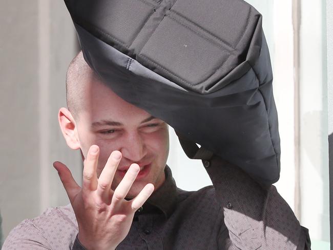 Guilty plea for Jack Gibson-Burrell, believed to be the man behind the notorious 'Pam the Bird' graffiti marks that have been covering the city, including Flinders Street's famous clock. He is pictured leaving the Melbourne Magistrate court trying to hide behind a bag with his lawyer on left. Friday, August 30. 2024. Picture: David Crosling