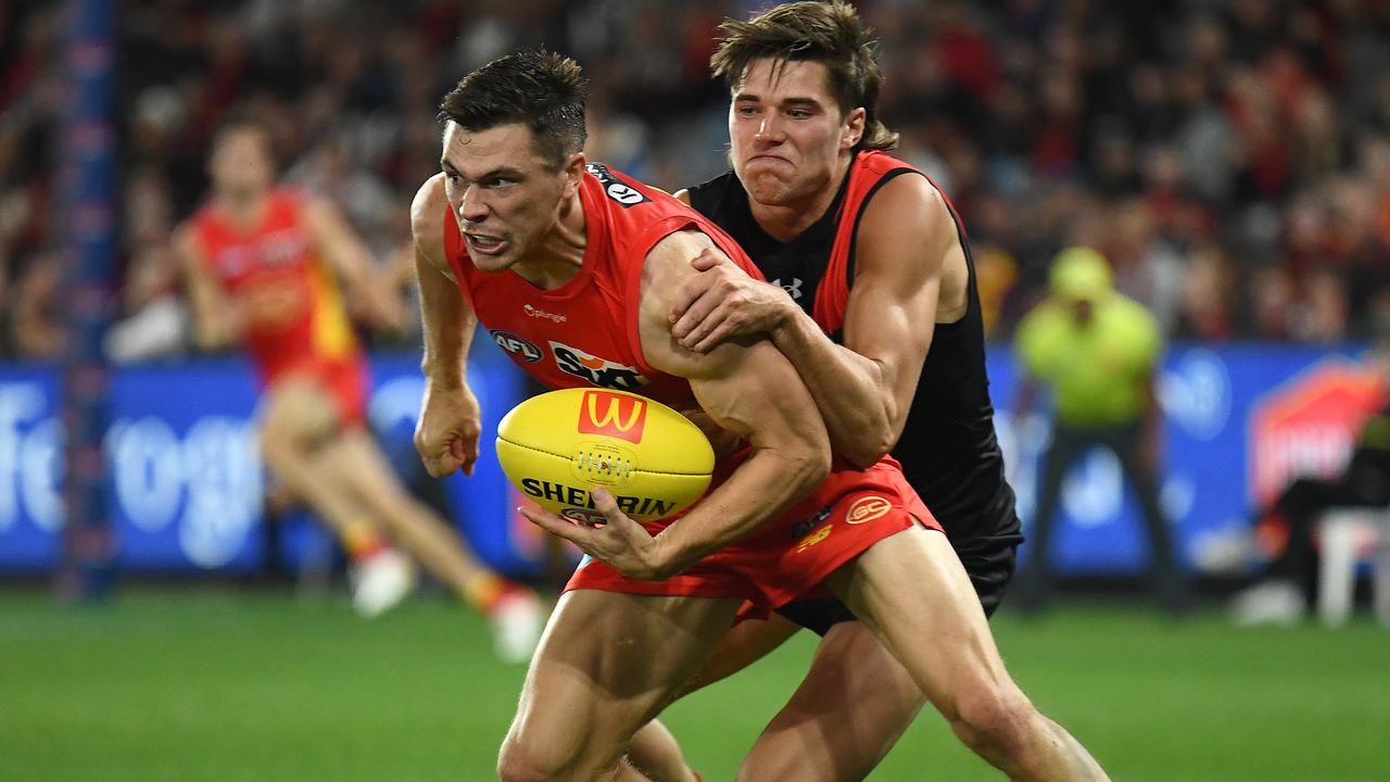 MELBOURNE, AUSTRALIA - MARCH 26: Ben Ainsworth of the Suns handballs whilst being tackled by Sam Durham of the Bombers during the round two AFL match between Essendon Bombers and Gold Coast Suns at Marvel Stadium, on March 26, 2023, in Melbourne, Australia. (Photo by Quinn Rooney/Getty Images)