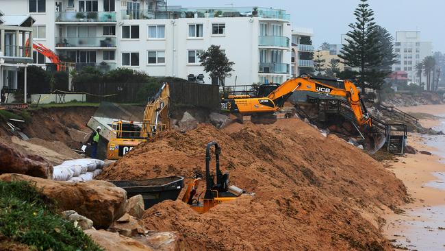 Workers build a sand wall with excavators to shore up damaged properties along the beachfront. Picture: Troy Snook