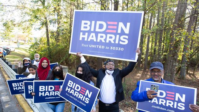 Gwinnett county voters including Menar Hague (C) wave Biden-Harris campaign signs at the entrance to Lucky Shoals Park polling station in Norcross, Georgia. Picture: AFP