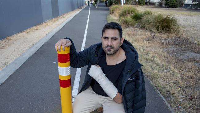 An injured Andrew Neocli next to the bollard that caused him to break three bones in his wrist. Picture: Andy Brownbill