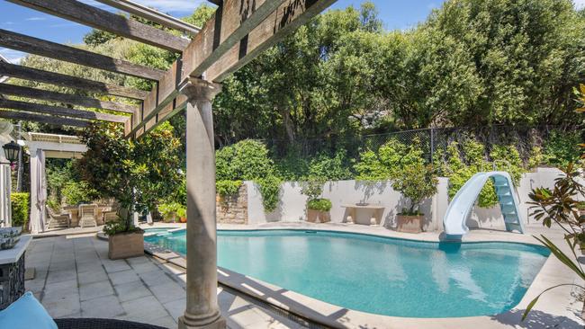 The pool with a slide and outdoor entertaining space.